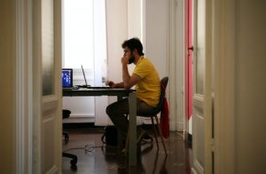 man sitting at a kitchen table with computer