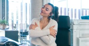 employee hugging herself - workplace wellness mobile chair massage maryland Corporate Massage Kneads Maryland